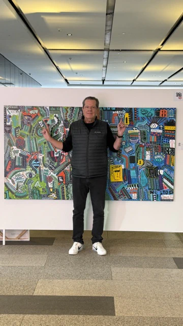 Alessandro standing between two exhibited canvases.
